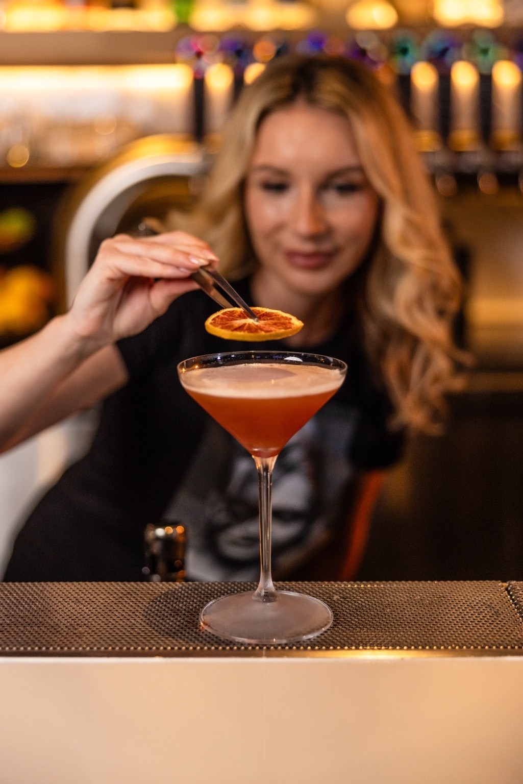 A bartender finishing a cocktail with a dried citrus wheel.