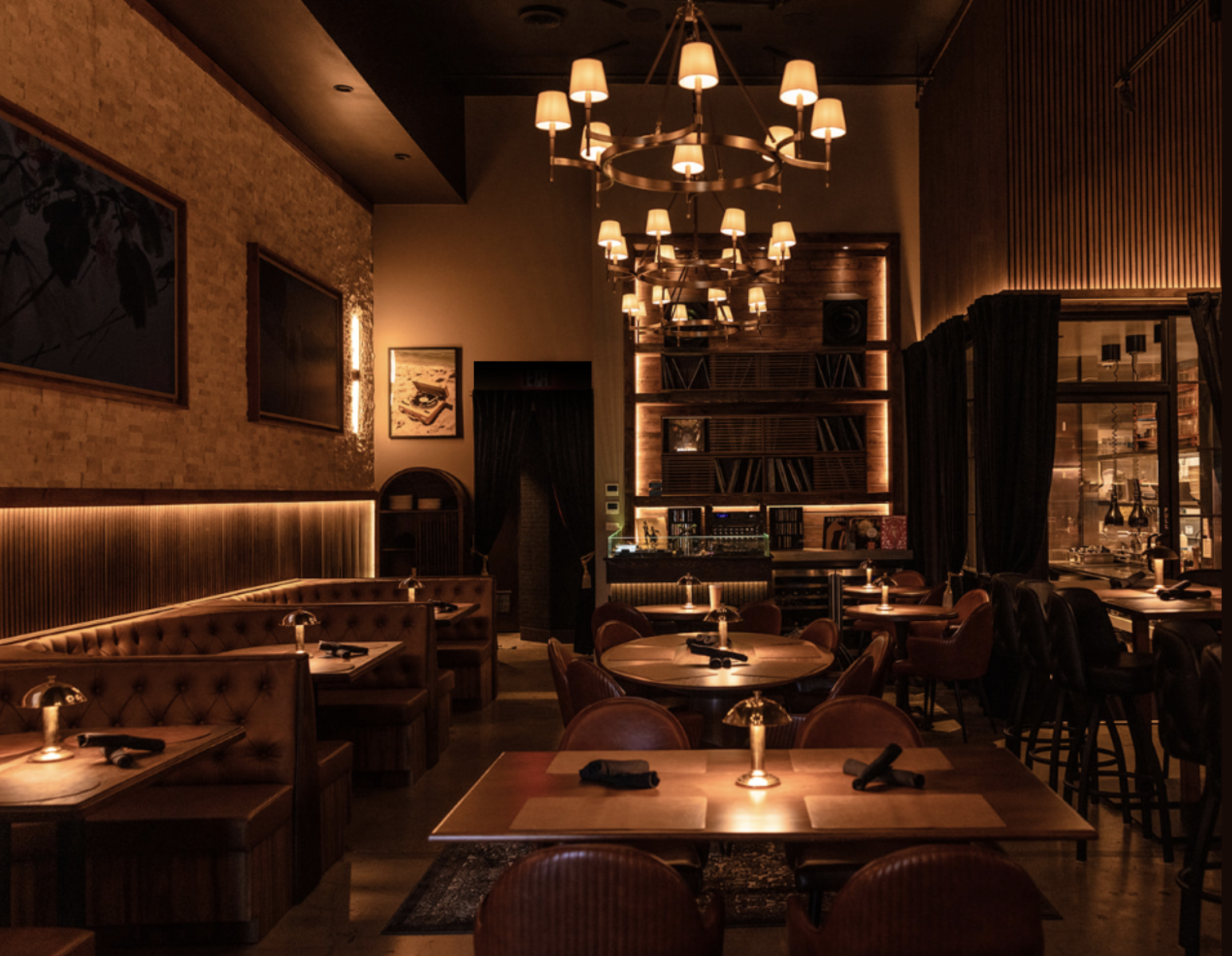 The dining room at Kasai Records before service — brass chandeliers, tufted banquettes and the lit record wall.