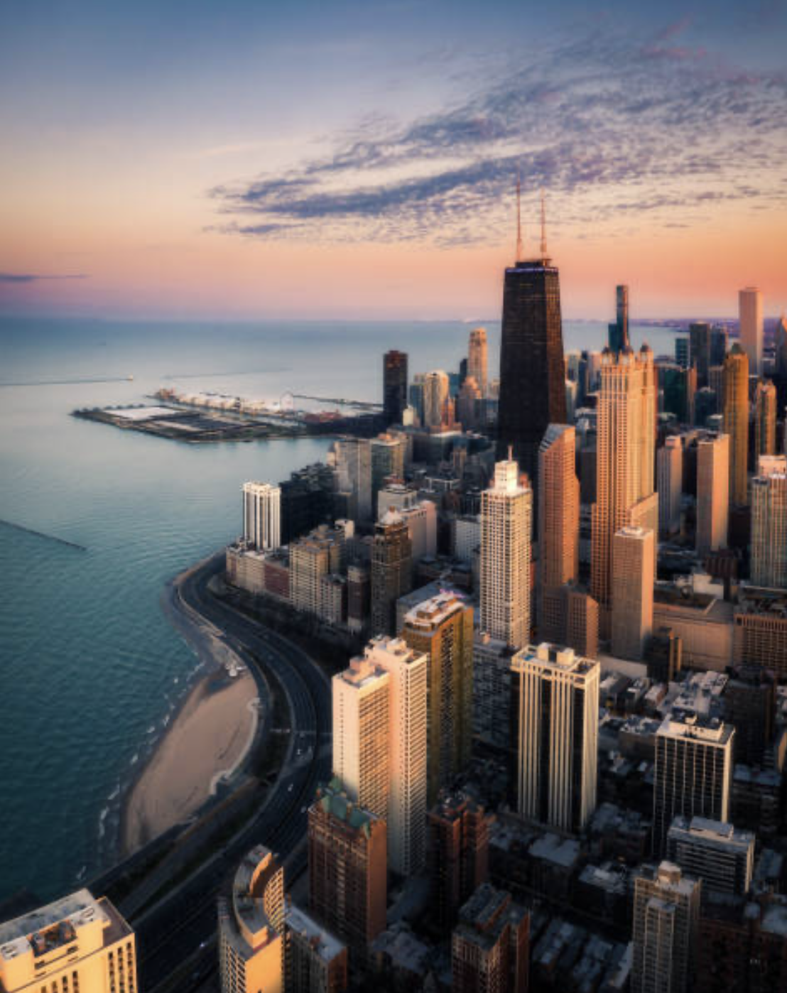Chicago from above at sunset — the Gold Coast towers along Lake Shore Drive with the lake and Navy Pier beyond.